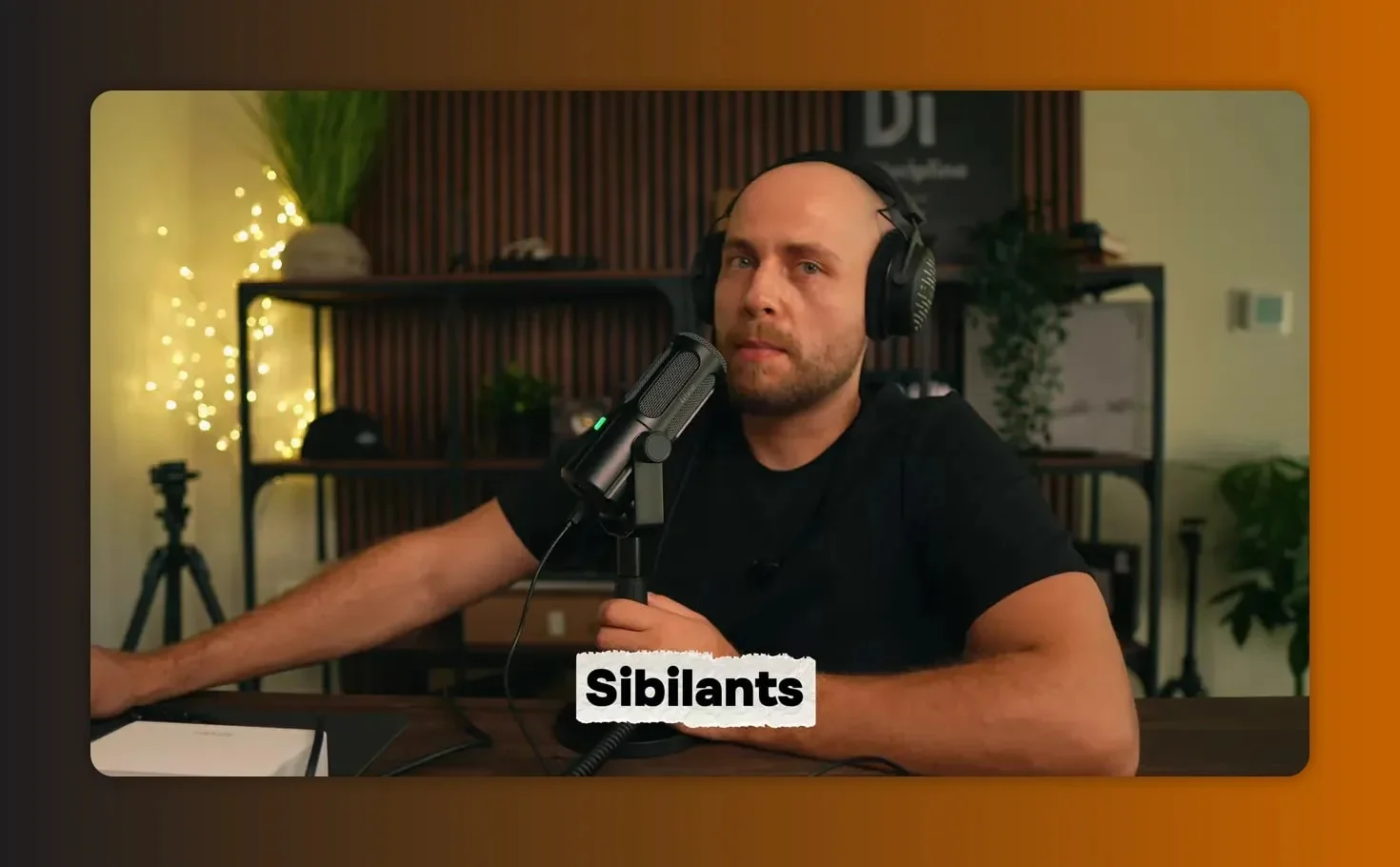 Balanced shot of presenter and Fifine Tank 6 microphone with 'Sibilants' label on-screen, used for sibilance testing.