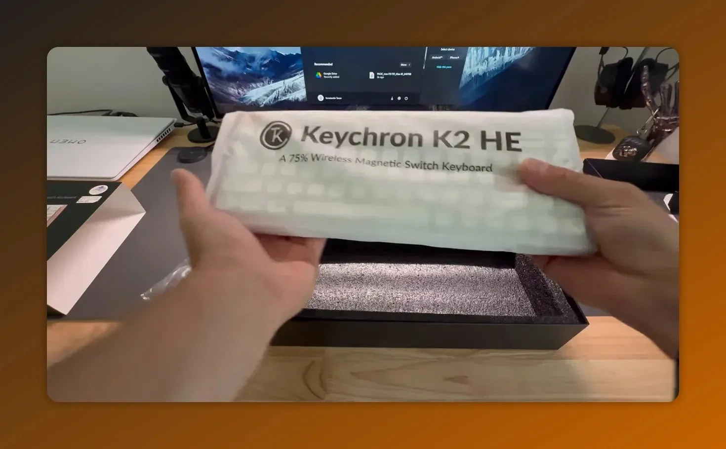 Hands lifting the Keychron K2 HE keyboard from its protective sleeve showing the product name
