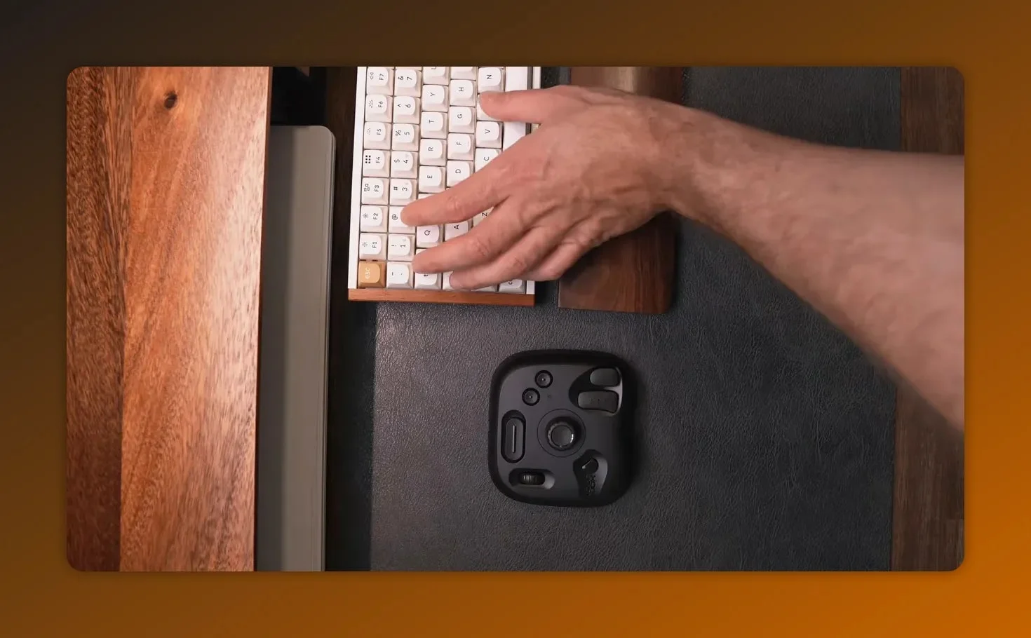 Hand pointing at the keyboard while a controller sits on the desk