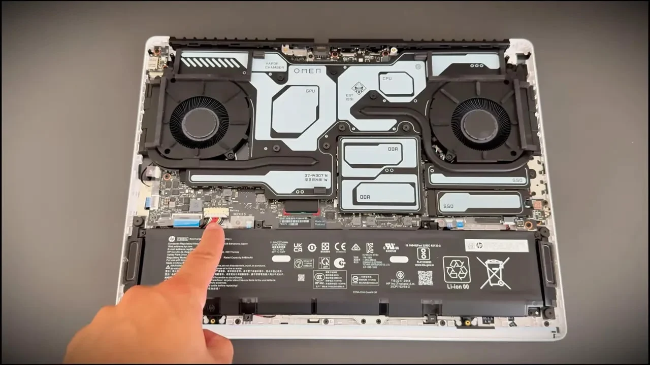 Finger pointing to the internal battery connector on an open HP Omen Max 16