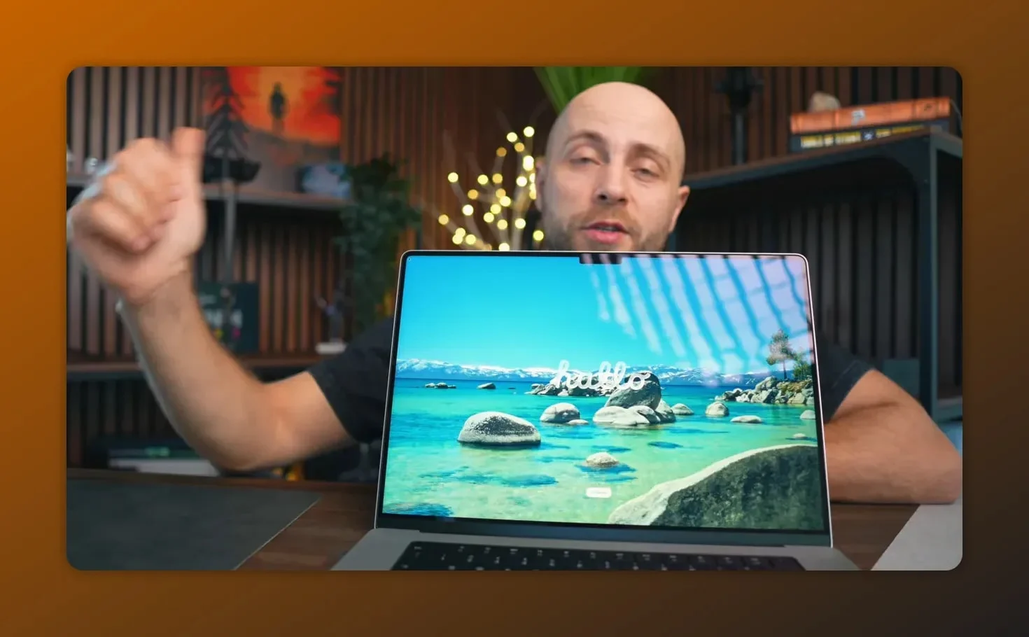 Presenter showing the MacBook Pro M5 Max display with landscape wallpaper